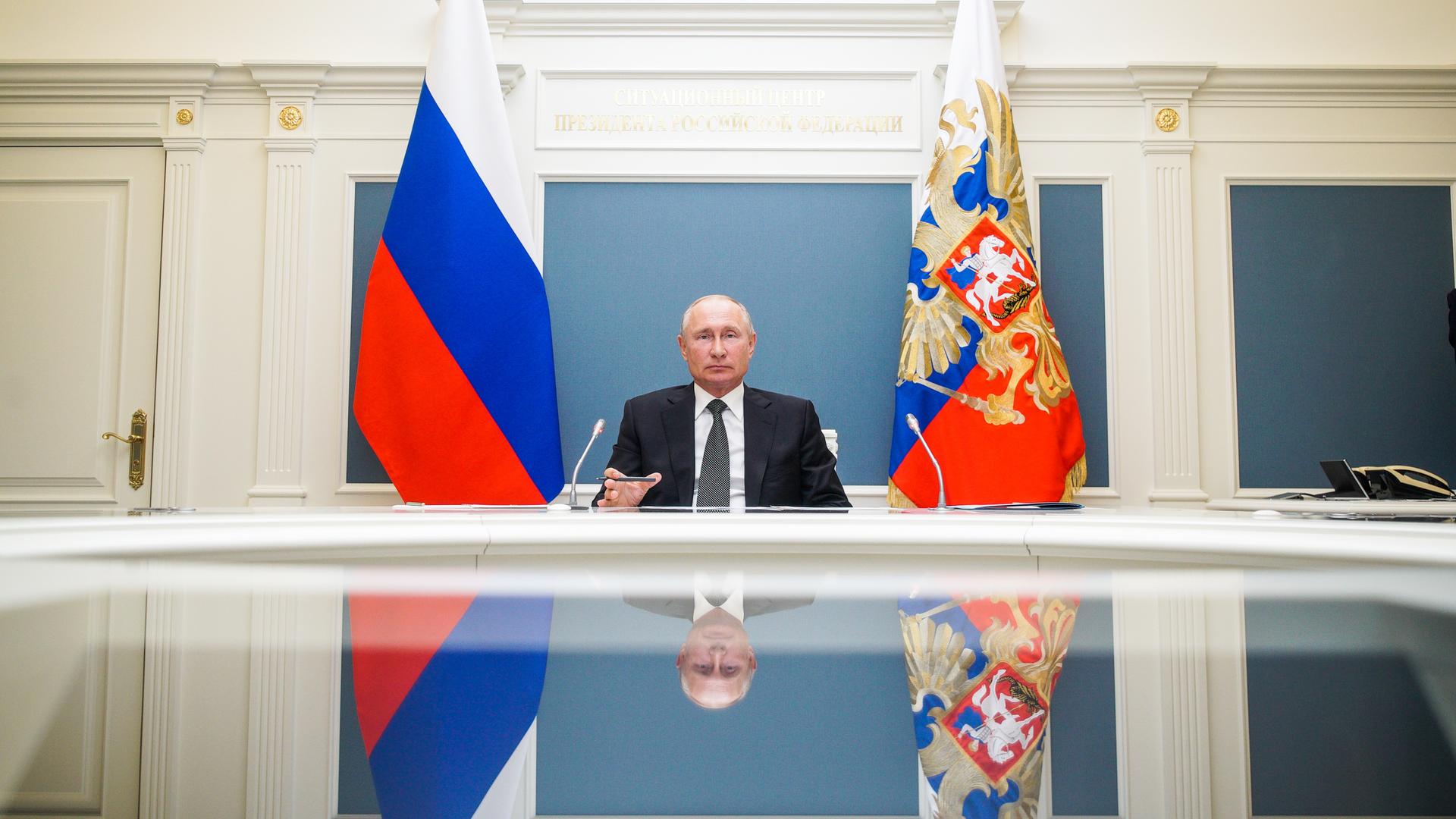 Russlands Präsident Wladimir Putin an einem Schreibtisch, hinter ihm Fahnen Russlands Präsident Wladimir Putin an einem Schreibtisch, hinter ihm Fahnen