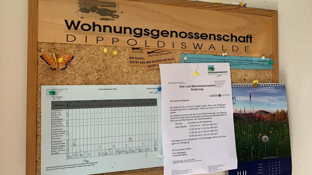 An einer Pinnwand mit der Aufschrift "Wohnungsgenossenschaft Dippoldiswalde" hängt unter anderem der Aushang, der das zeitweise Abschalten der Warmwasseraufbereitung ankündigt. 