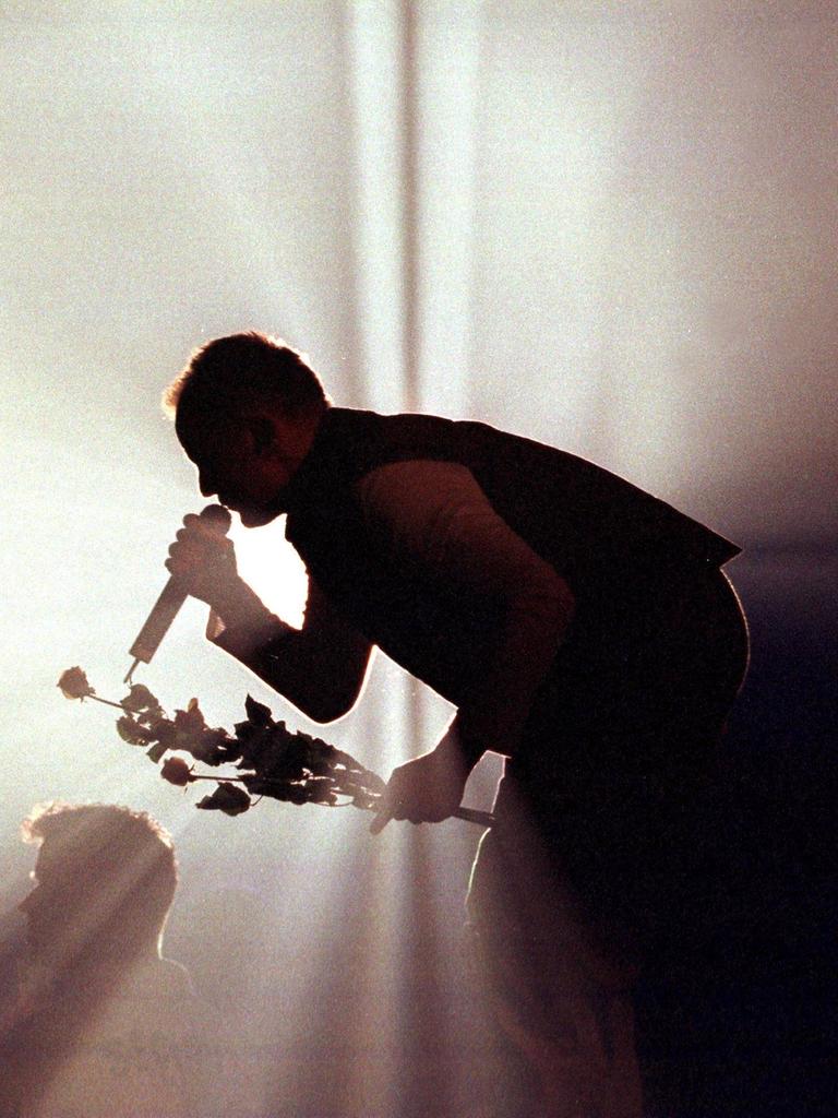 Die Silhouette von Herbert Grönemeyer im grobkörnigen Gegenlicht eines Scheinwerfers während eines Konzerts zum Zeitpunkt seines Albums Mensch.