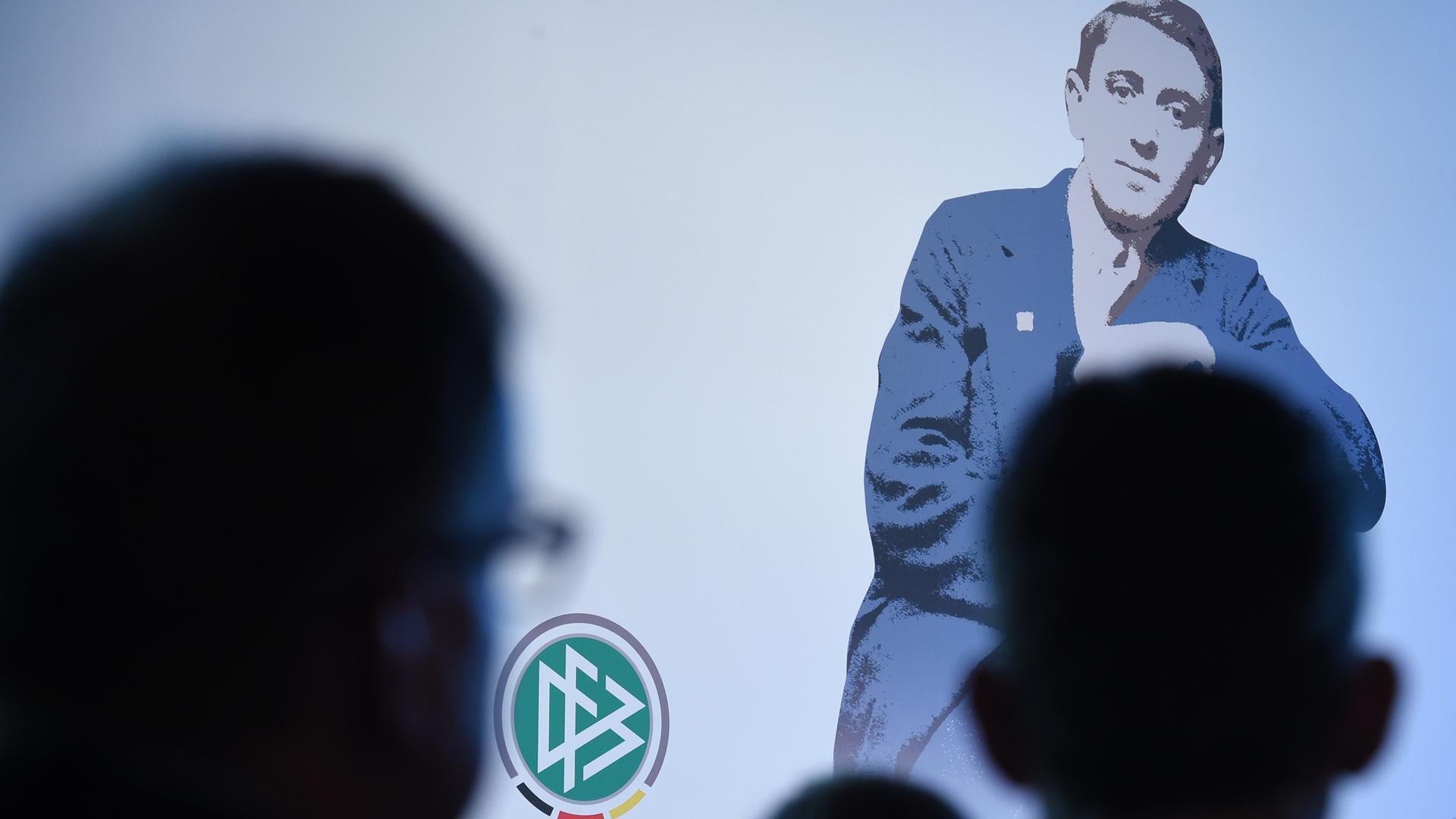 Ein Bild von Julius Hirsch bei der Preisverleihung, das Publikum ist im Schatten von hinten aufgenommen Ein Bild von Julius Hirsch bei der Preisverleihung, das Publikum ist im Schatten von hinten aufgenommen
