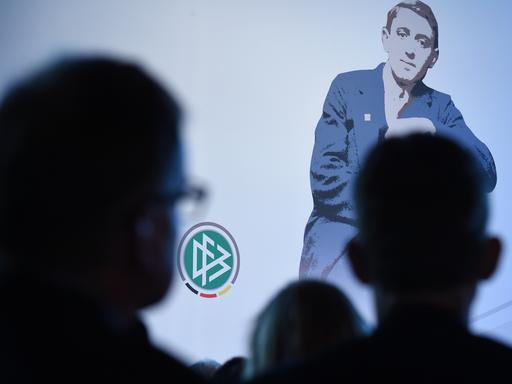 Ein Bild von Julius Hirsch bei der Preisverleihung, das Publikum ist im Schatten von hinten aufgenommen