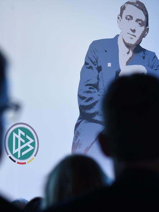 Ein Bild von Julius Hirsch bei der Preisverleihung, das Publikum ist im Schatten von hinten aufgenommen