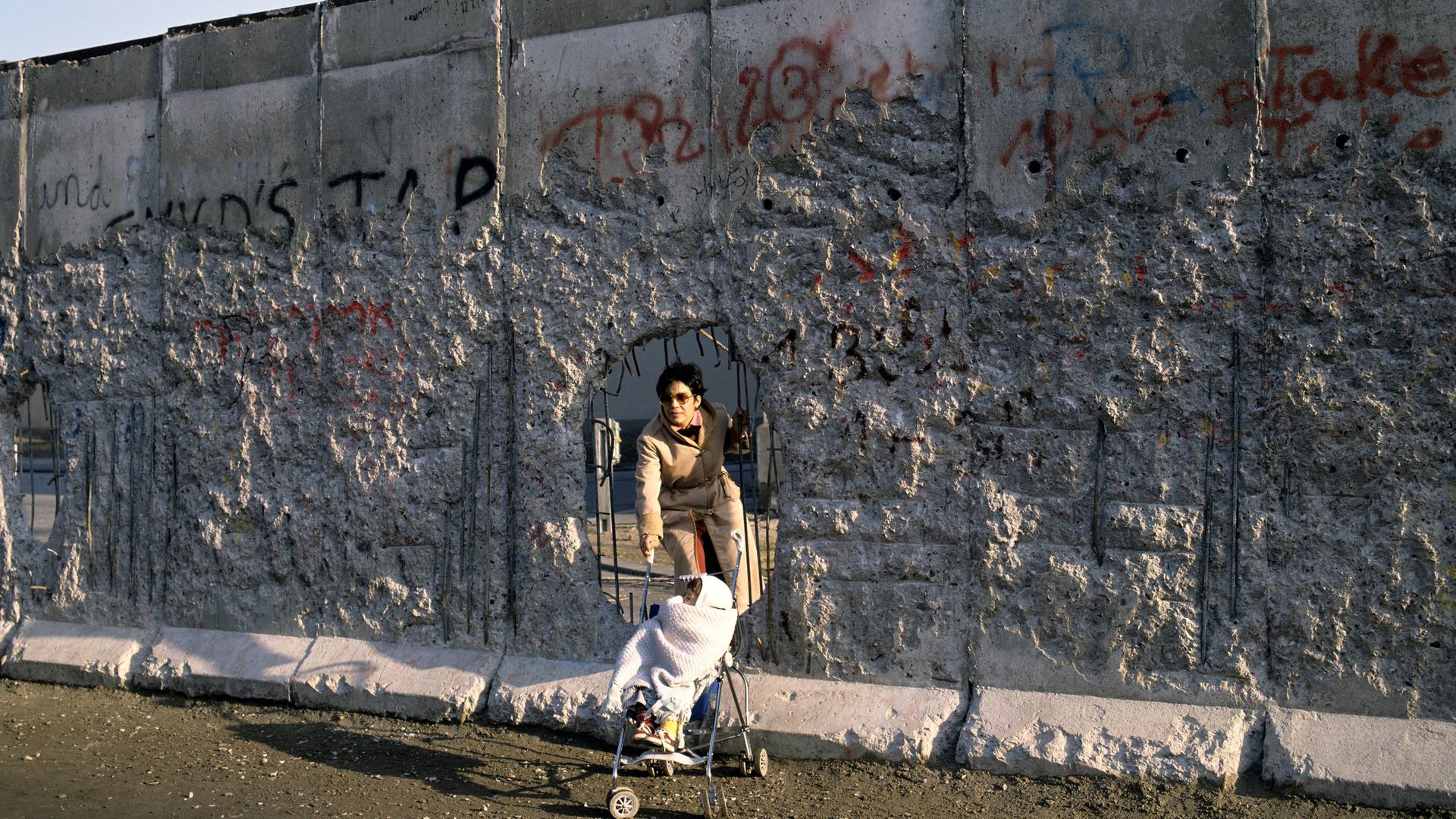 Mutter und Kind gehen durch ein Loch in der Berliner Mauer. Das Bild ist vom Dezember 1989. Mutter und Kind gehen durch ein Loch in der Berliner Mauer. Das Bild ist vom Dezember 1989.