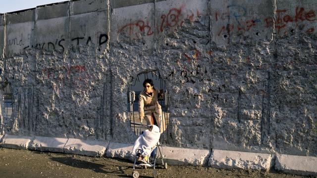 Mutter und Kind gehen durch ein Loch in der Berliner Mauer. Das Bild ist vom  Dezember 1989.