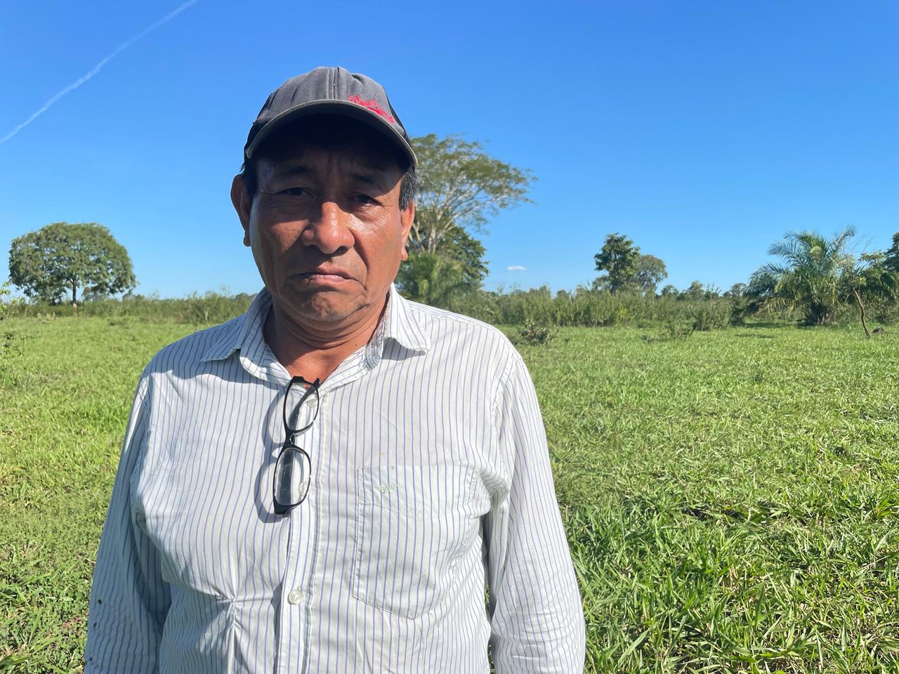 Ein missmutig schauender älterer Mann mit Käppi und gestreiftem Hemd steht auf einem grünen Feld. Ein missmutig schauender älterer Mann mit Käppi und gestreiftem Hemd steht auf einem grünen Feld.