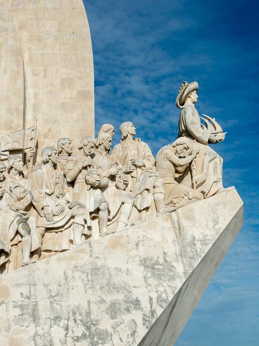 Das Foto zeigt das Denkmal für die Entdeckungen am Ufer des Flusses Tejo in Lissabon. Darauf abgebildet sind u.a. Heinrich der Seefahrer, Vasco da Gama und viele andere koloniale Entdecker. 