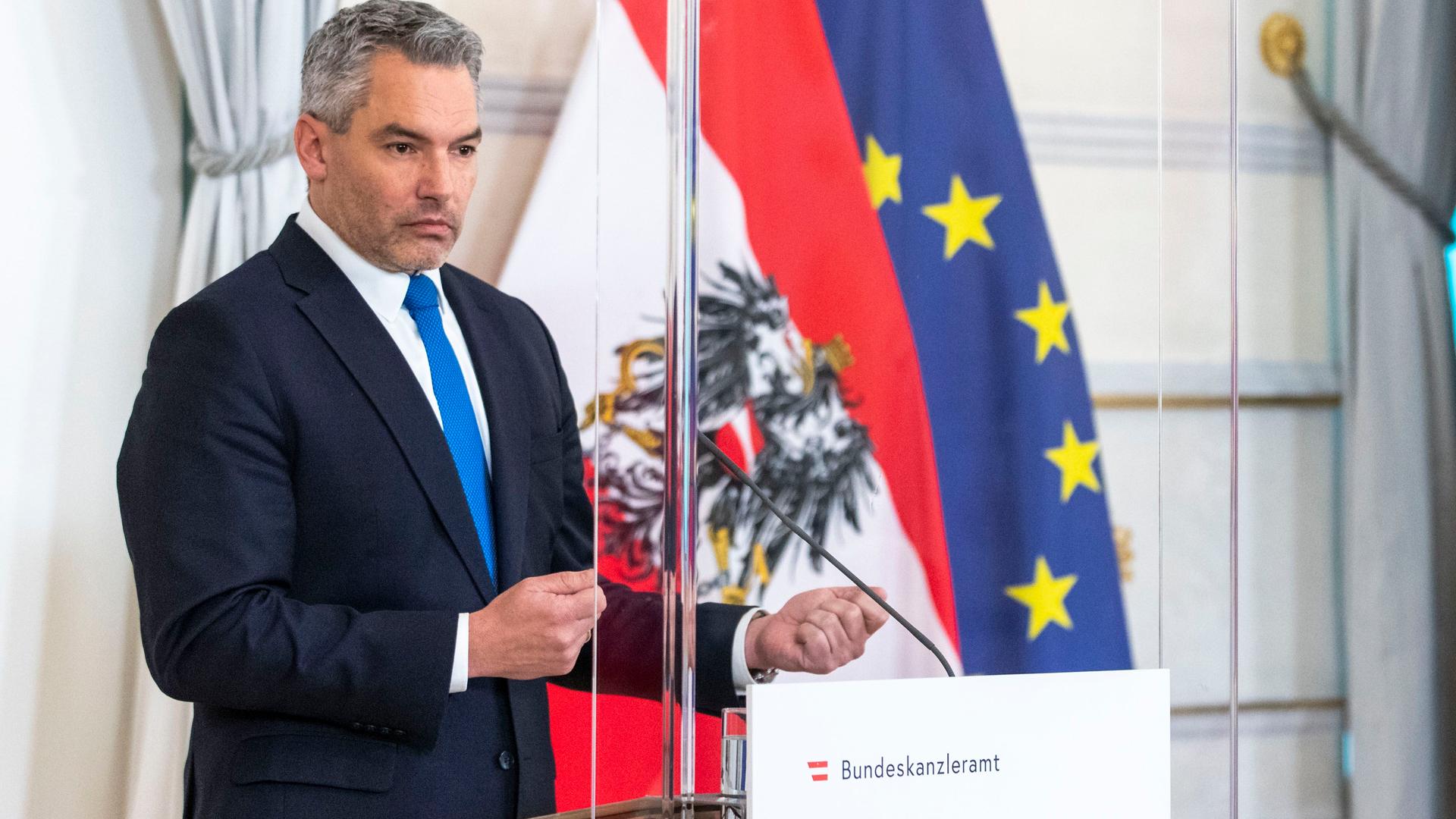 Der österreichische Bundes-Kanzler Nehammer steht vor einem Mikrofon. Der österreichische Bundes-Kanzler Nehammer steht vor einem Mikrofon.