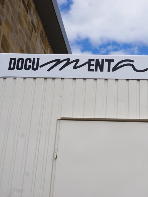 Auf einem Container vor dem Documentagelände in Kassel prangt die Aufschrift "Documenta Fifteen". Die Fenster des Containers sind geschlossen.