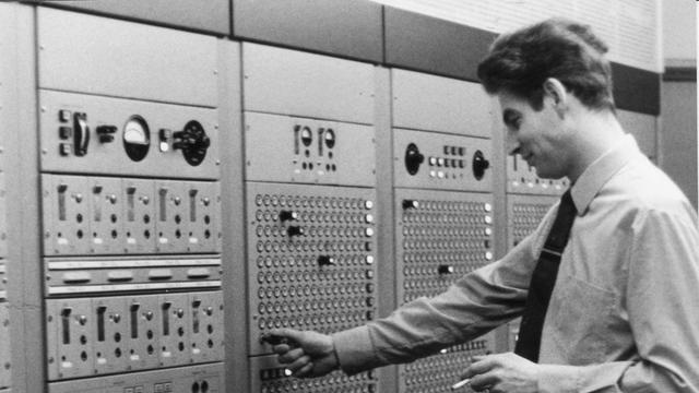 Schwarz-Weiß-Aufnahme eines Mannes, der im Schaltraum eines Radiosenders steht