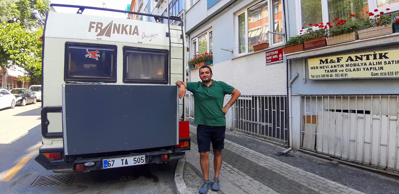 Ein junger Mann in Shorts und grünem T-Shirt lehnt an der Rückseite eine Wohnmobils. Ein junger Mann in Shorts und grünem T-Shirt lehnt an der Rückseite eine Wohnmobils.