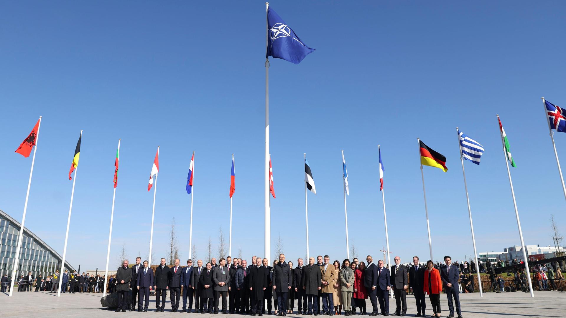 本部での外相会議の傍観式でフィンランドの国旗が掲げられた後、NATOの外相は加盟国の旗の前で写真を撮るために集まります。