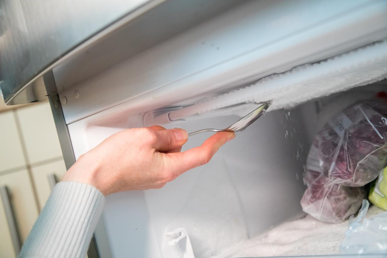 Eine Frau kratzt in einer Kueche in Hamburg den mit einem Loeffel Eis aus dem Tiefkuehlfach (gestellte Szene). Eine Frau kratzt in einer Kueche in Hamburg den mit einem Loeffel Eis aus dem Tiefkuehlfach (gestellte Szene).