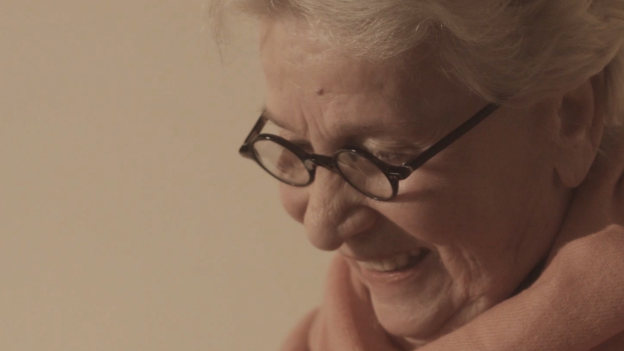 Eine Dame mit Brille schaut lächelnd nach unten Eine Dame mit Brille schaut lächelnd nach unten