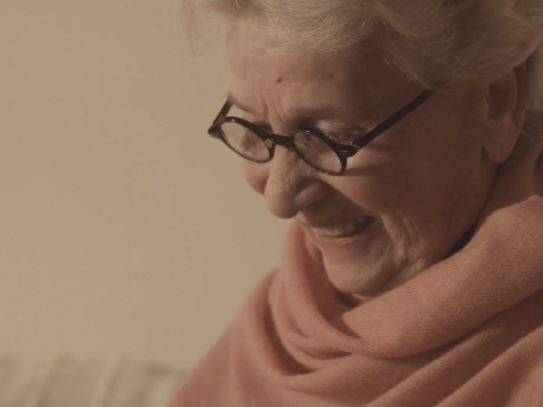 Eine Dame mit Brille schaut lächelnd nach unten
