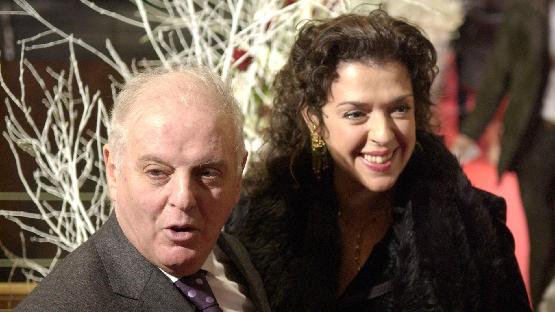 Das Ehepaar Barenboim-Bashkirova lächelt nebeneinander stehend bei einer Festveranstaltung in Konzertkleidung in die Kamera.