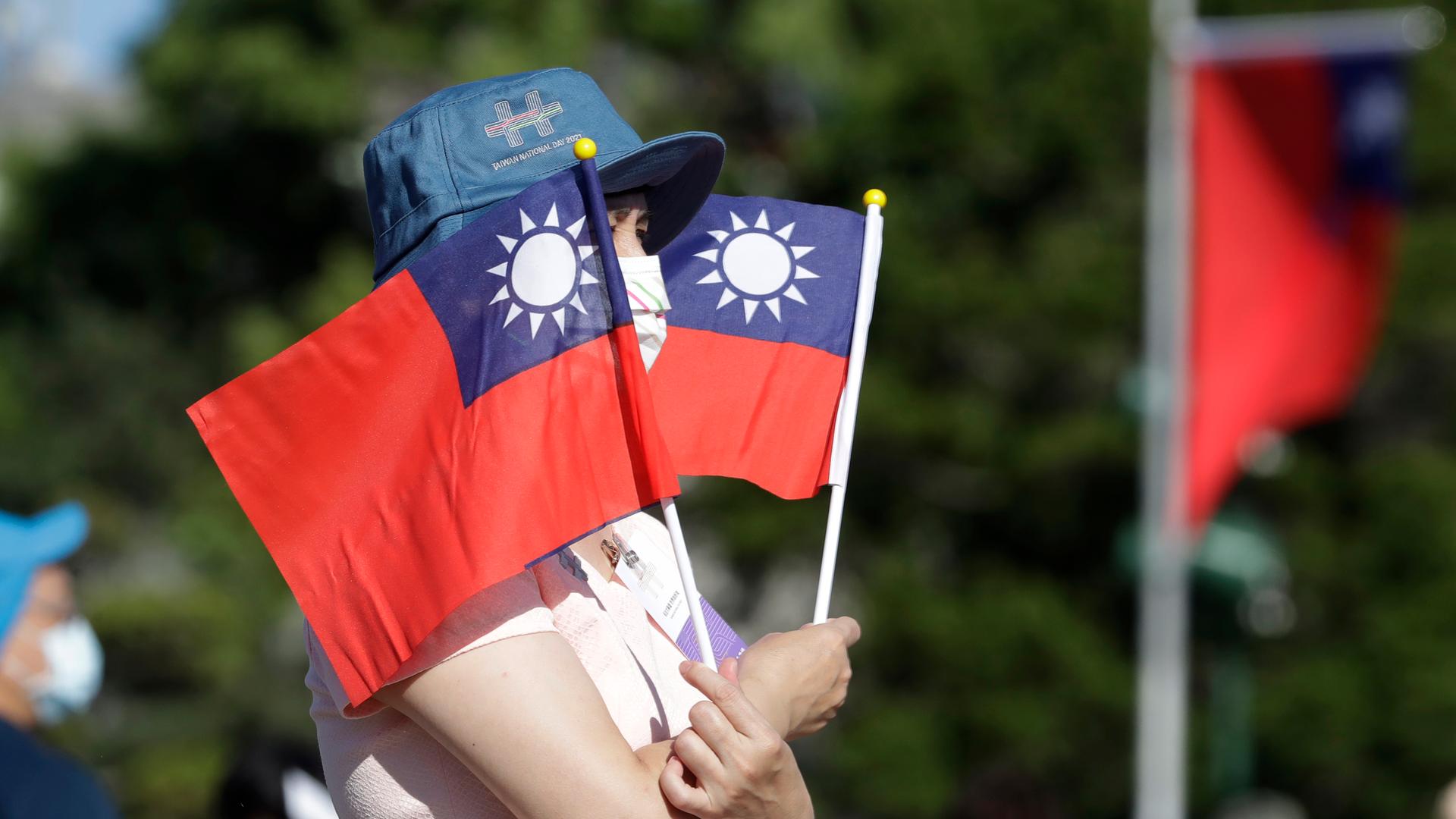 Eine Frau hält zwei taiwanesische Flaggen Eine Frau hält zwei taiwanesische Flaggen