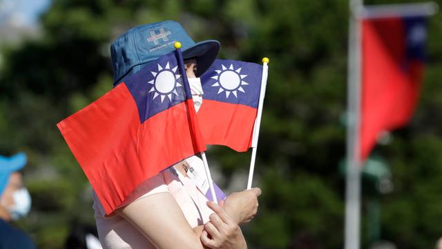 Eine Frau hält zwei taiwanesische Flaggen