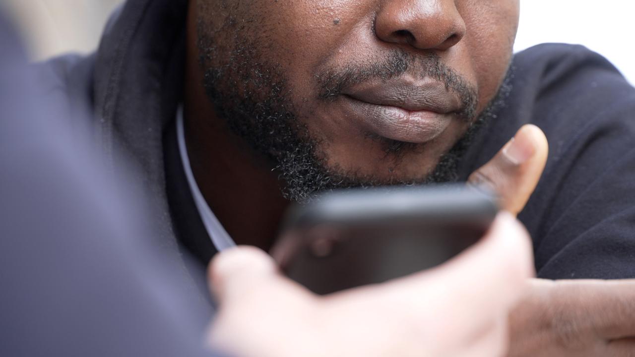 Informant aus Nigeria hört sich Audionachricht auf Handy an .
