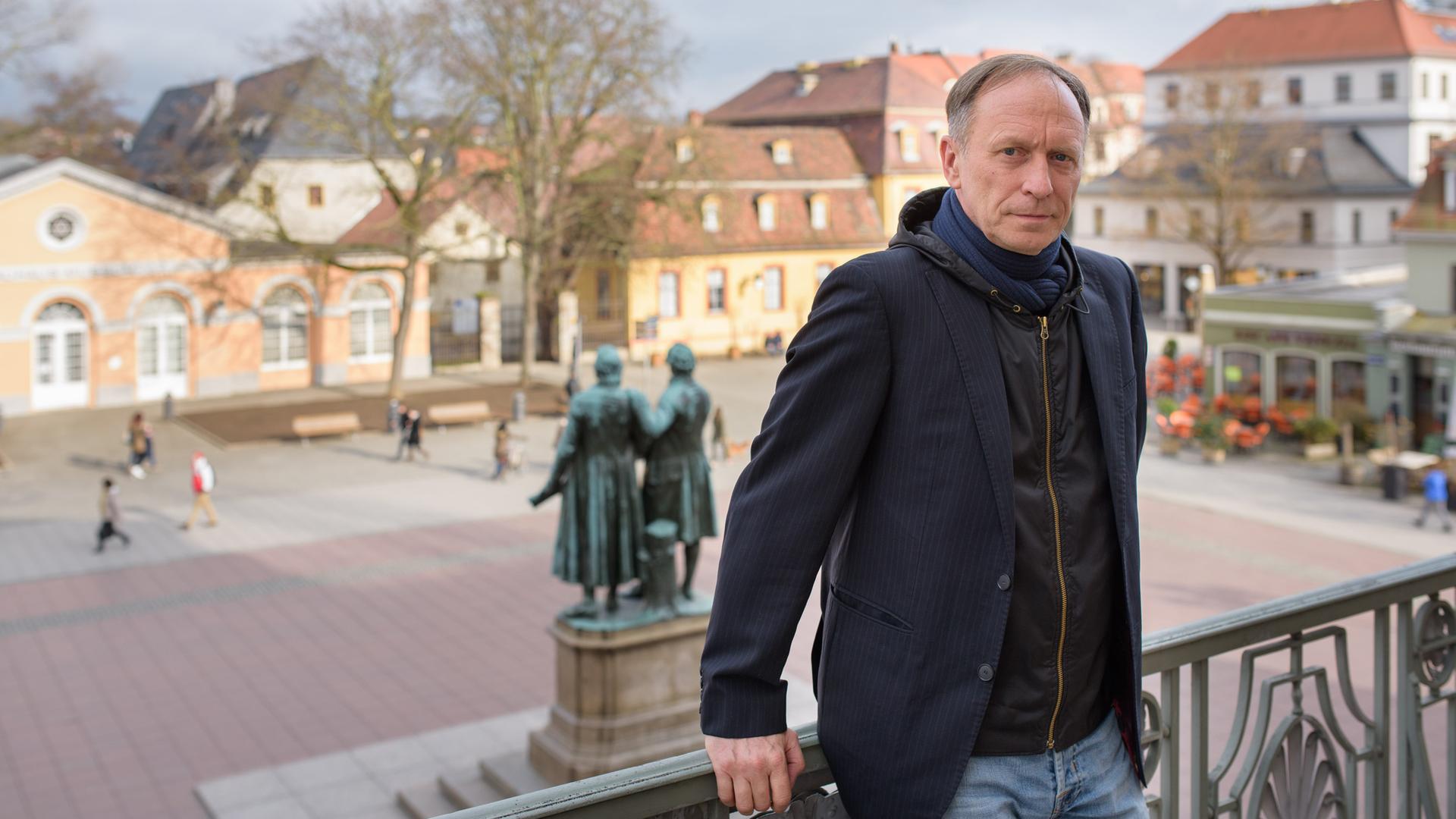 Ein Mann mittleren Alters steht am 07.03.2017 auf dem Balkong des Deutschen Nationaltheater in Weimar (Thüringen), im Hintergrund ein Denkmal von Goethe und Schiller Ein Mann mittleren Alters steht am 07.03.2017 auf dem Balkong des Deutschen Nationaltheater in Weimar (Thüringen), im Hintergrund ein Denkmal von Goethe und Schiller