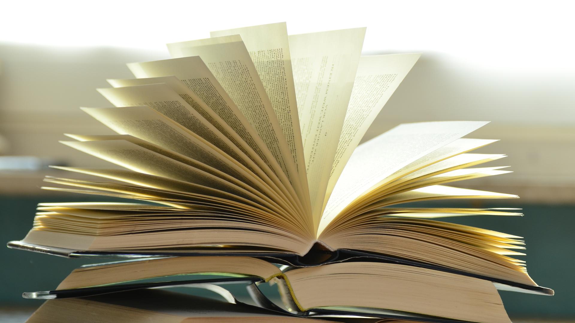 Ein Buchstapel mit einem geöffneten Buch. Ein Buchstapel mit einem geöffneten Buch.