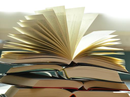 Ein Buchstapel mit einem geöffneten Buch. 