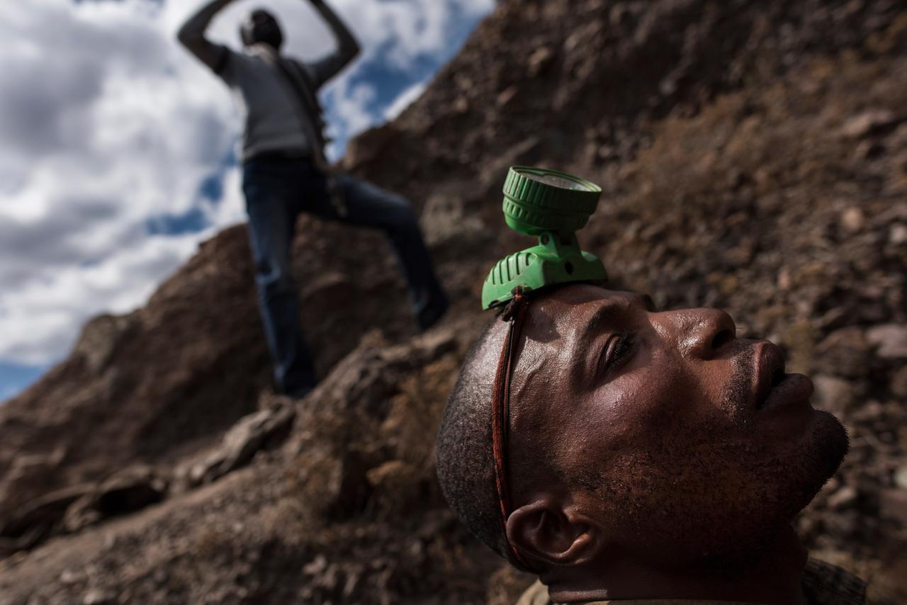 Ein Minenarbeiter mit einer Stirnlampe auf dem Kopf beim Einstieg in eine Kupfer- und Kobaltmine in Kawama / Kongo. Ein Minenarbeiter mit einer Stirnlampe auf dem Kopf beim Einstieg in eine Kupfer- und Kobaltmine in Kawama / Kongo.