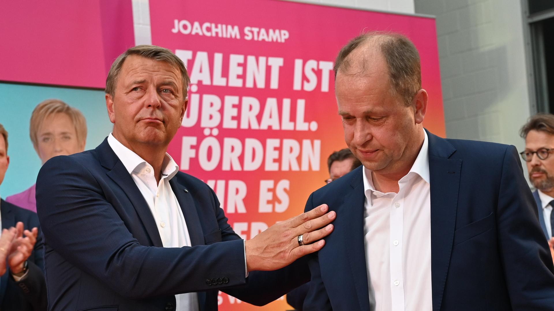Der FDP-Spitzenkandidat für die Landtagswahl in Nordrhein-Westfalen, Joachim Stamp (r), steht bei der Wahlparty seiner Partei auf der Bühne und wird von Christof Rasche, Vorsitzender der FDP-Landtagsfraktion NRW, getröstet