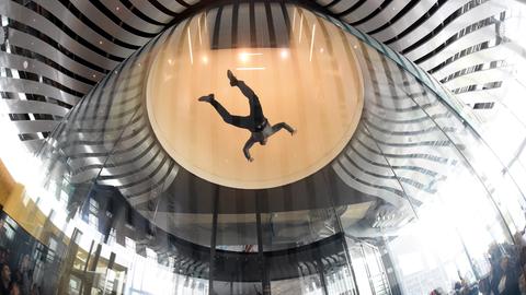 Ein Mensch fliegt oben in einer großen Glaskugel im Windkanal.