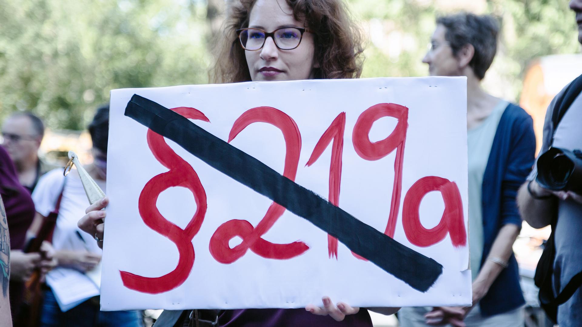 Protest gegen den Abtreibungsparagraf in Berlin, eine Frau hält ein Schild mit dem durchgestrichenen Pararafen 219a in der Hand.