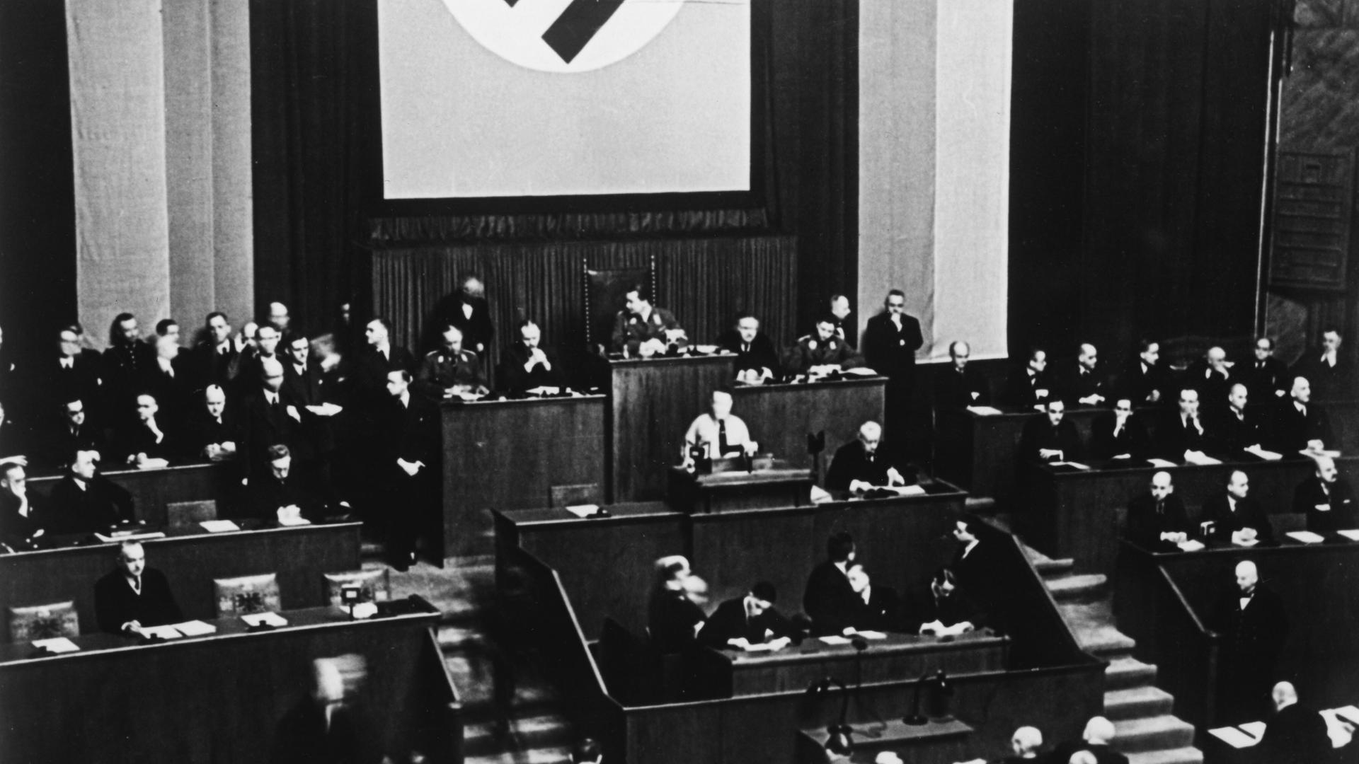 Das Schwarz-Weiß-Bild zeigt Adolf Hitler am Rednerpult des Reichstags unter der Hakenkreuzflagge am 23. März 1933 vor der Abstimmung über das "Gesetz zur Behebung der Not von Volk und Reich" - das sogenannte "Ermächtigungsgesetz".