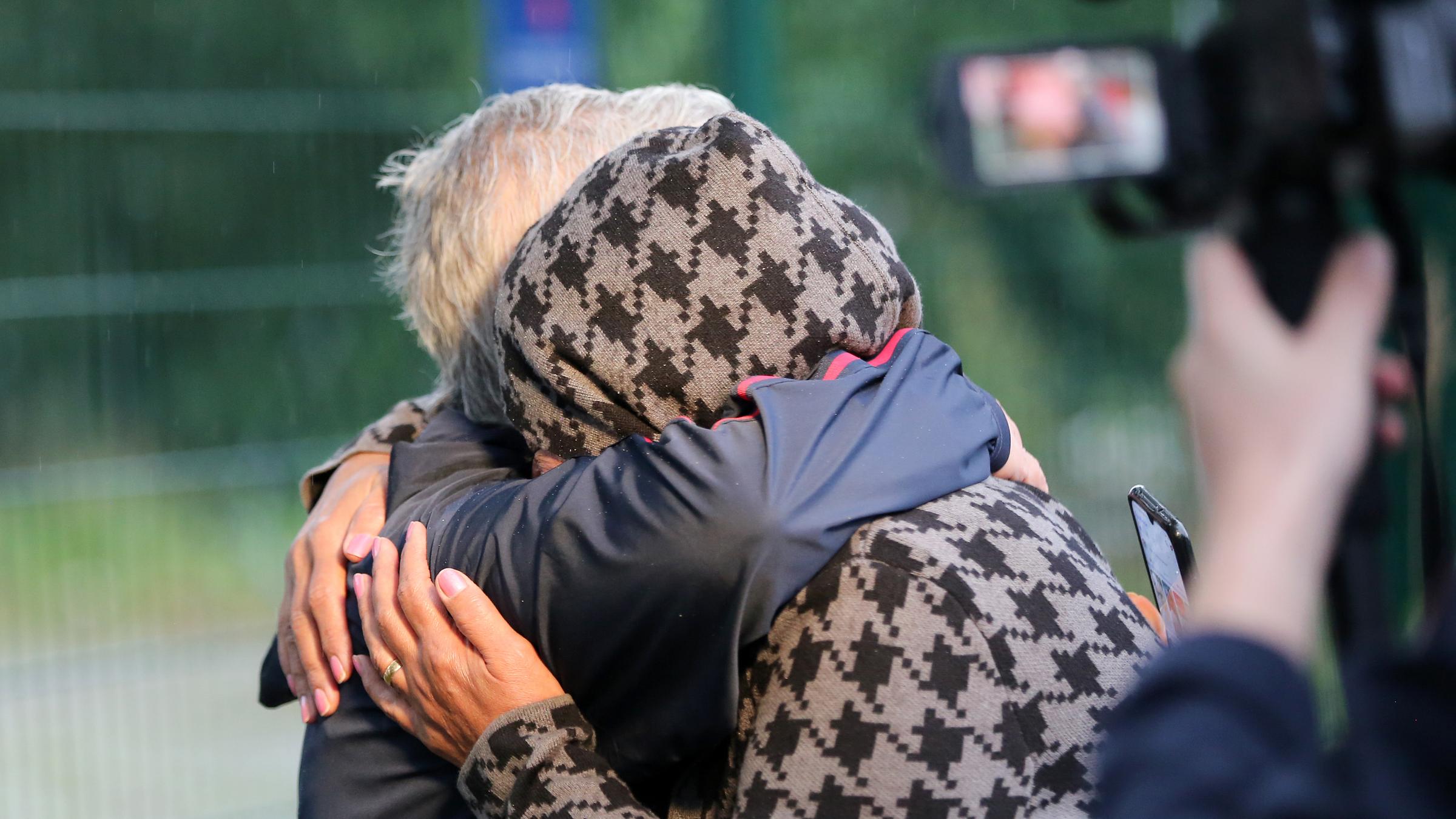 Menschen liegen sich nach der Ankunft eines Busses mit Menschen aus Afghanistan vor einer Aufnahmeeinrichtung in Hamburg-Rahlstedt in den Armen.