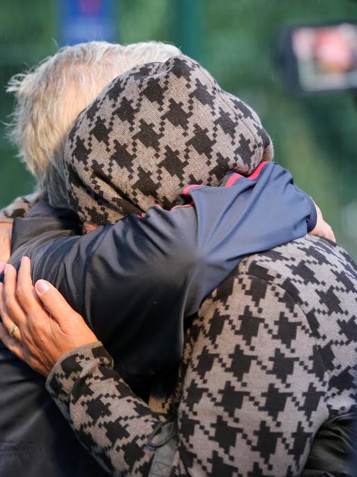Menschen liegen sich nach der Ankunft eines Busses mit Menschen aus Afghanistan vor einer Aufnahmeeinrichtung in Hamburg-Rahlstedt in den Armen.
