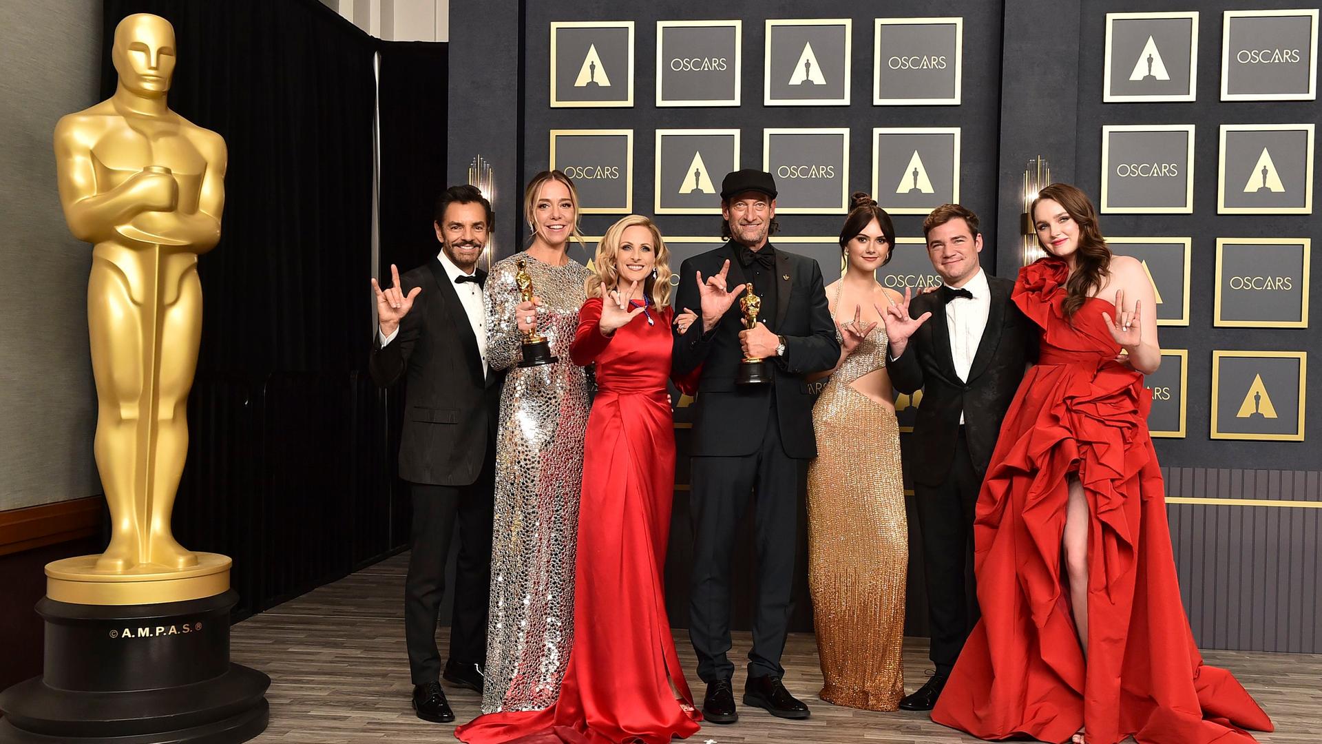 Los Angeles: Eugenio Derbez, Sian Heder, Marlee Matlin, Troy Kotsur, Emilia Jones, Daniel Durant und Amy Forsyth, Gewinner des Preises für den besten Film "Coda", zeigen im Presseraum der 94. Verleihung der Academy Awards in Hollywood ihre Oscars und das Gebärdenzeichen für "I Love You". Neben ihnen steht eine lebensgroße Oscarstatue. Los Angeles: Eugenio Derbez, Sian Heder, Marlee Matlin, Troy Kotsur, Emilia Jones, Daniel Durant und Amy Forsyth, Gewinner des Preises für den besten Film "Coda", zeigen im Presseraum der 94. Verleihung der Academy Awards in Hollywood ihre Oscars und das Gebärdenzeichen für "I Love You". Neben ihnen steht eine lebensgroße Oscarstatue.
