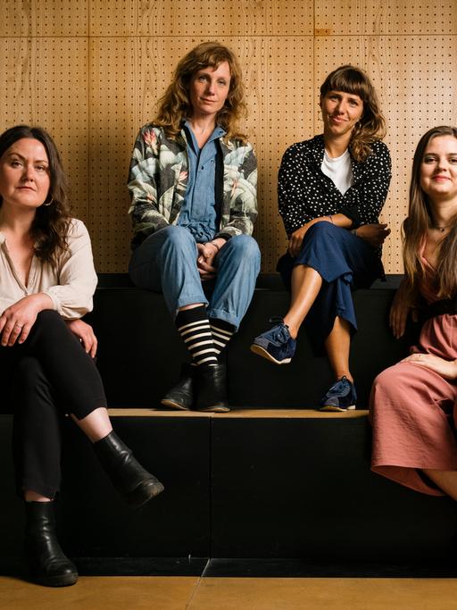 Vier Frauen sitzen nebeneinander in einem Theater.