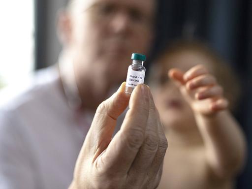 Ein Kinderarzt hält Impfstoff in der Hand.