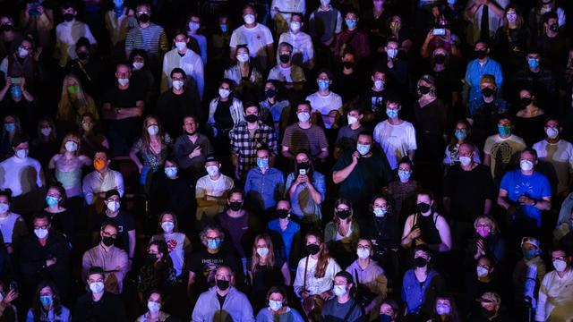 Zuschauer verfolgen stehend ein Konzert in der Kölner Philharmonie. Sie tragen Masken gegen das Coronavirus.