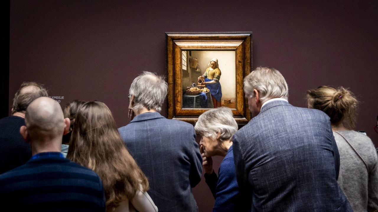 Besucherinnen und Besucher stehen im Rijksmuseum in Amsterdam vor Vermeers "Dienstmagd mit Milchkrug".