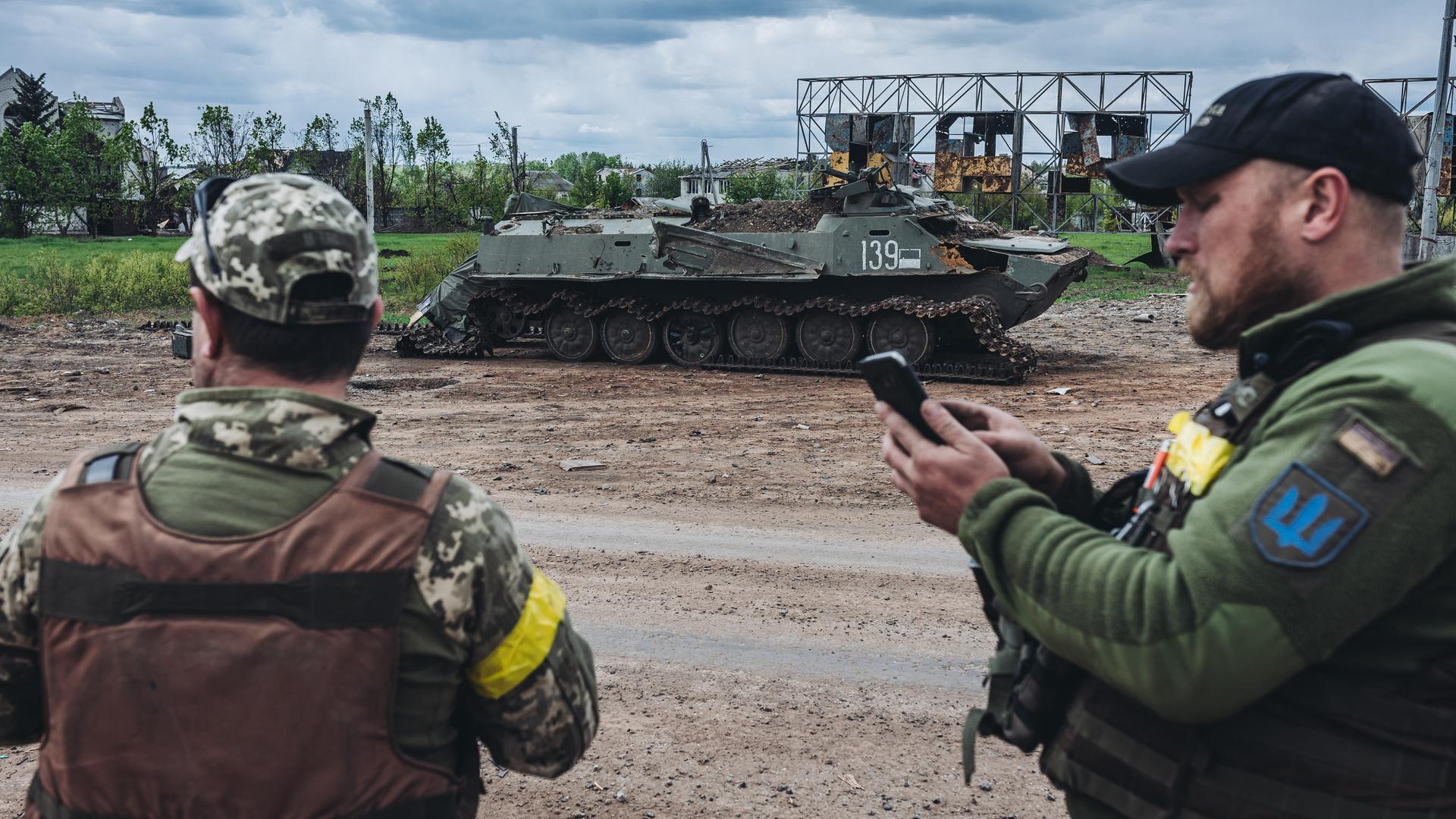 Ukrainische Soldaten vor einem zerstörten Militärfahrzeug Ukrainische Soldaten vor einem zerstörten Militärfahrzeug
