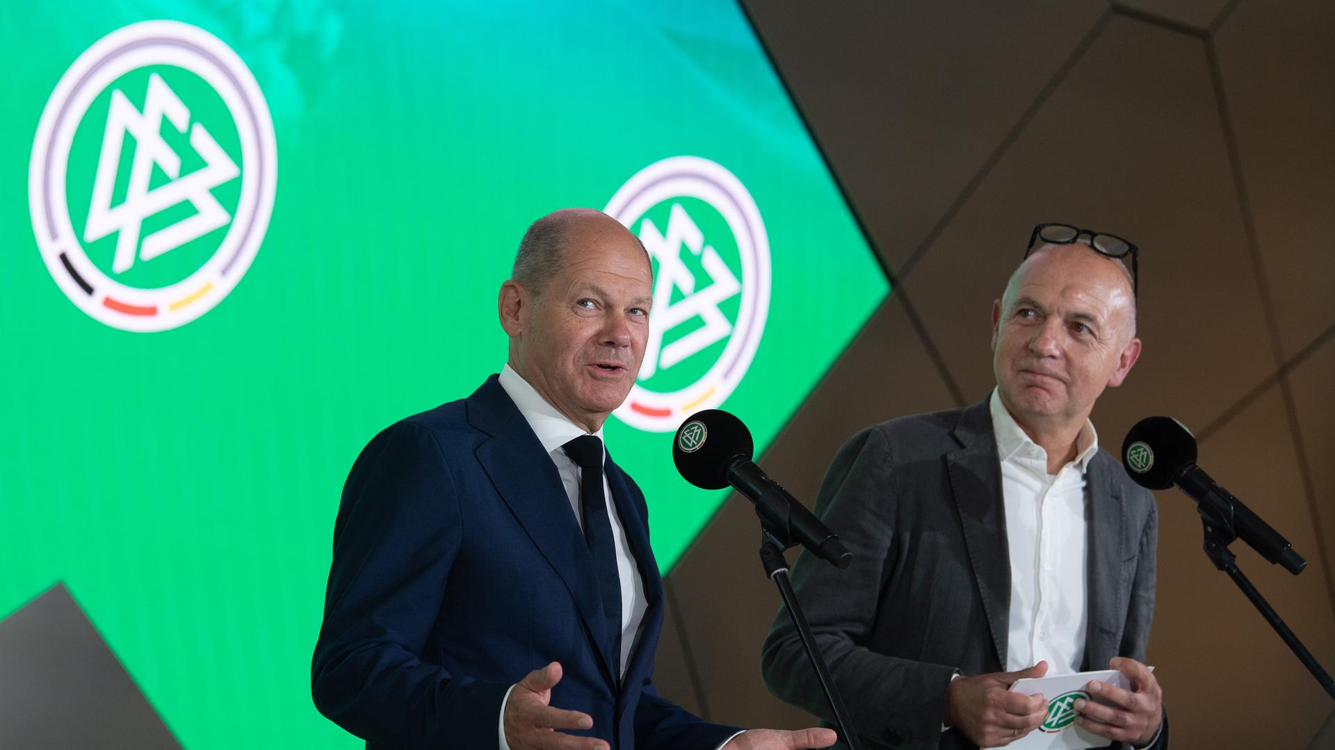 Bundeskanzler Olaf Scholz (SPD, l) spricht während eines Besuchs des DFB-Campuses. Bernd Neuendorf, DFB-Präsident sieht ihn von der Seite aus an. Bundeskanzler Olaf Scholz (SPD, l) spricht während eines Besuchs des DFB-Campuses. Bernd Neuendorf, DFB-Präsident sieht ihn von der Seite aus an.