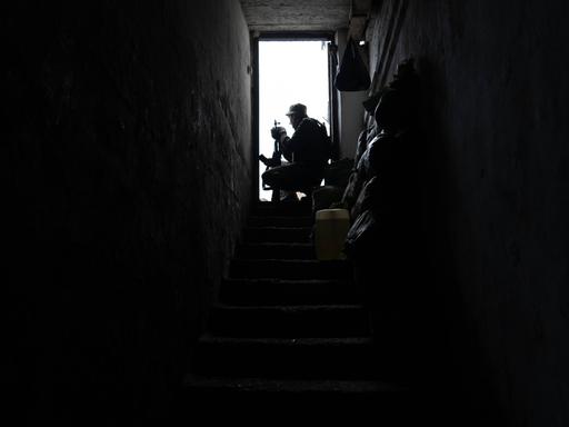 Ein ukrainischer Soldat sitzt an einer geöffneten Tür am Ende einer langen Treppe, der Raum ist dunkel, die Szene ist von einem Stützpunkt nahe Soledar, in der Donezk Region, 25. April 2023