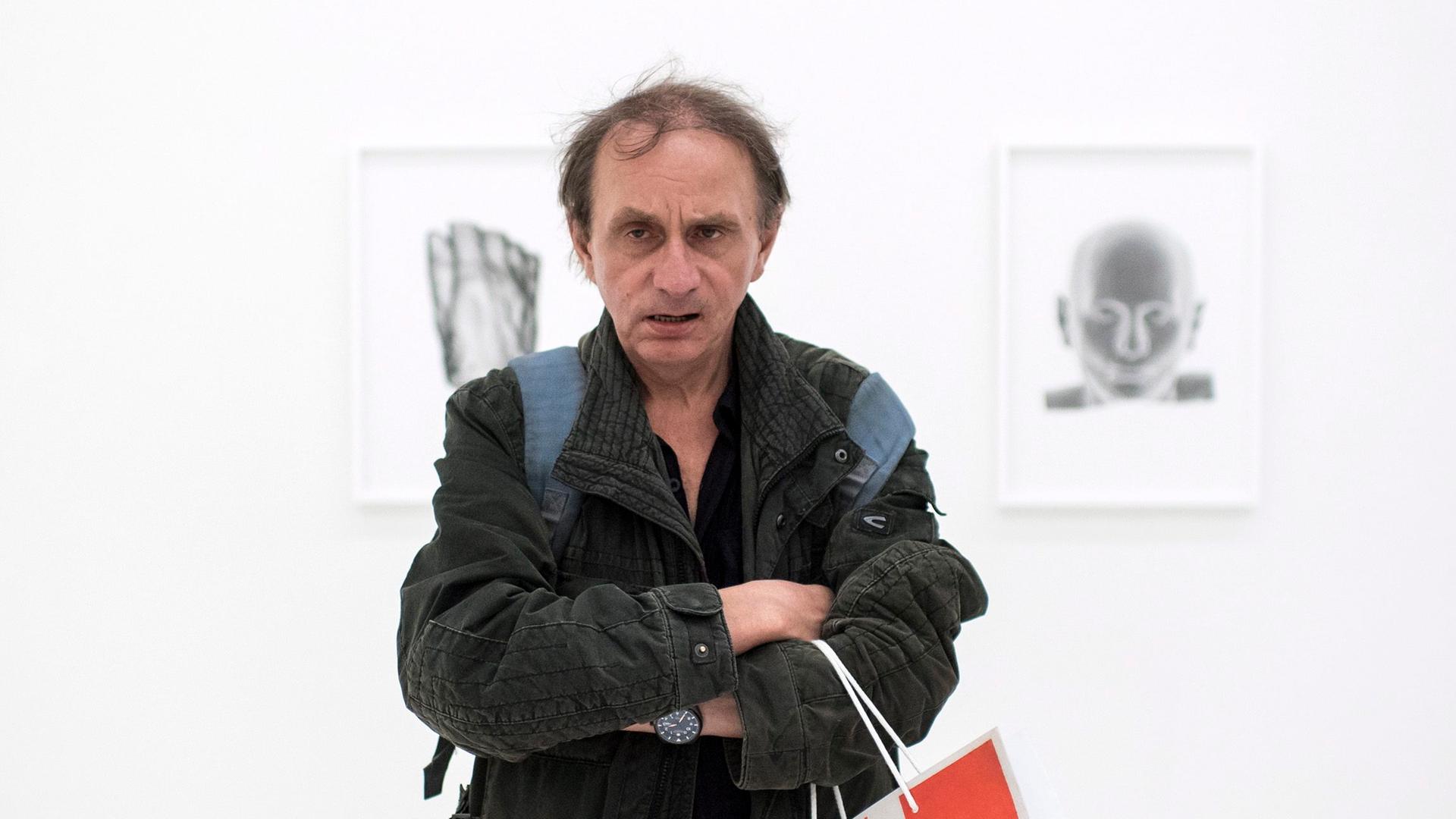 Michel Houellebecq posiert auf der europäischen Biennale vor einem seiner Werke Michel Houellebecq posiert auf der europäischen Biennale vor einem seiner Werke