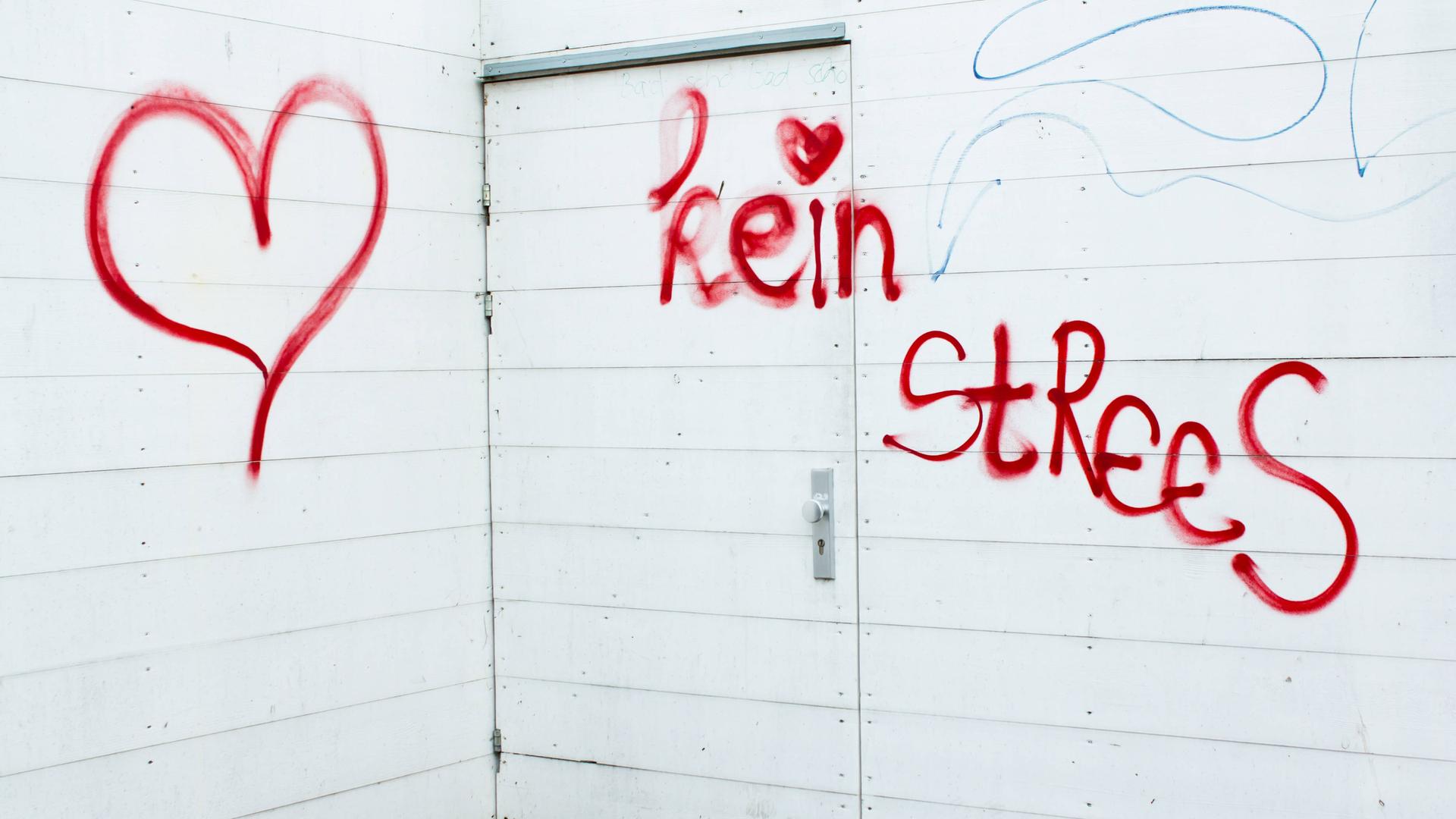 Ein rotes Graffiti an einer Wand: "Kein Strees" mit Herz daneben.