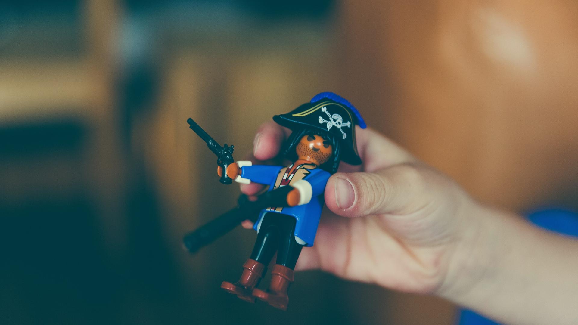 Eine Hand hält ein Playmobil-Piratenmännchen. Eine Hand hält ein Playmobil-Piratenmännchen.