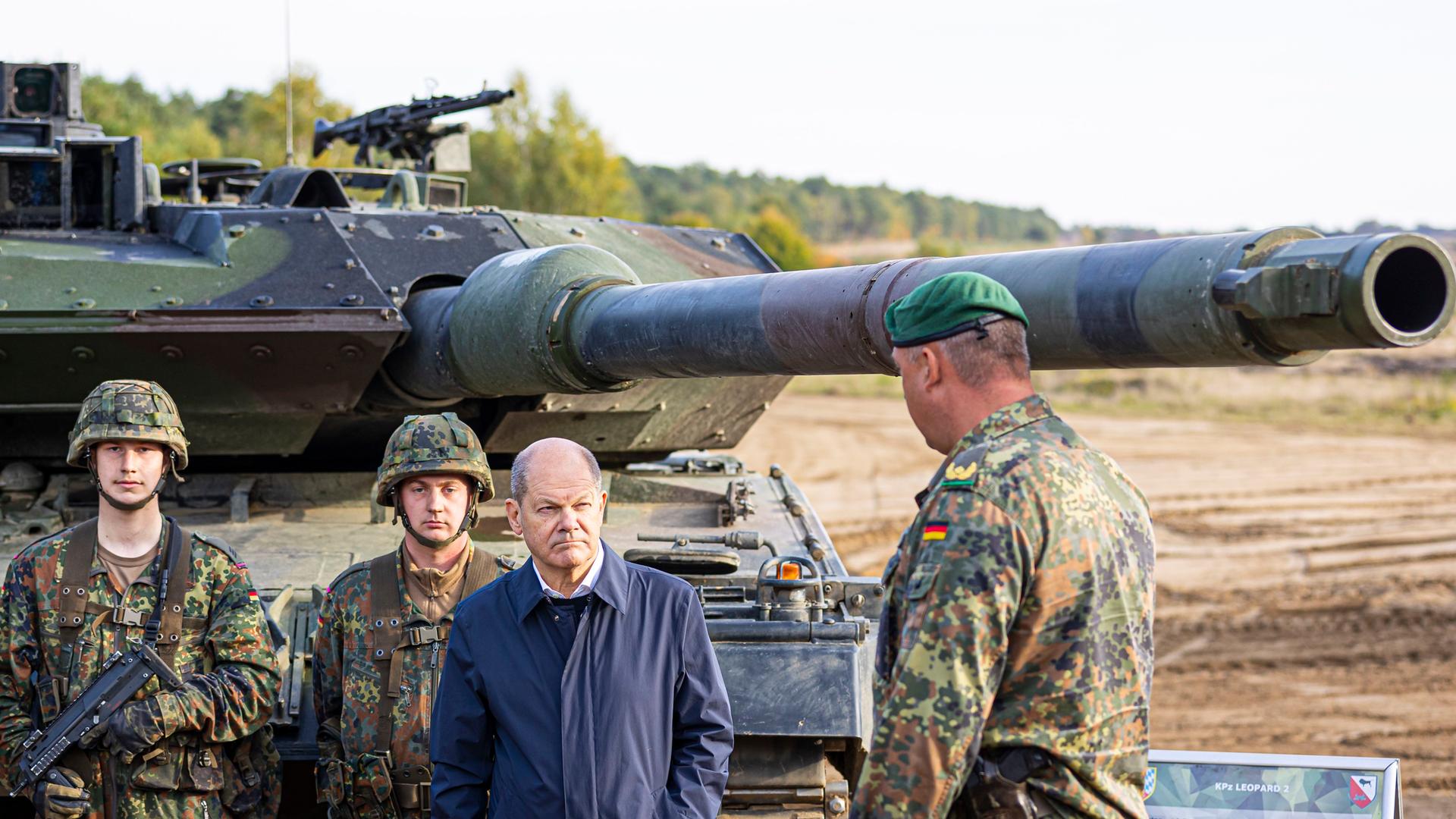 Bundeskanzler Olaf Scholz (SPD, 2.v.r) lässt sich vor der Ausbildungs- und Lehrübung des Heeres im Landkreis Heidekreis in der Lüneburger Heide den Kampfpanzer "Leopard 2" der Bundeswehr erklären.