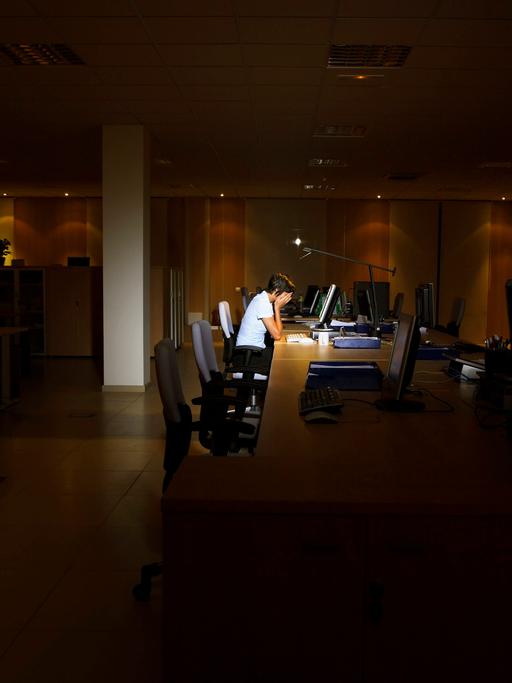 Müde einsame Person vor einem Bürorechner.