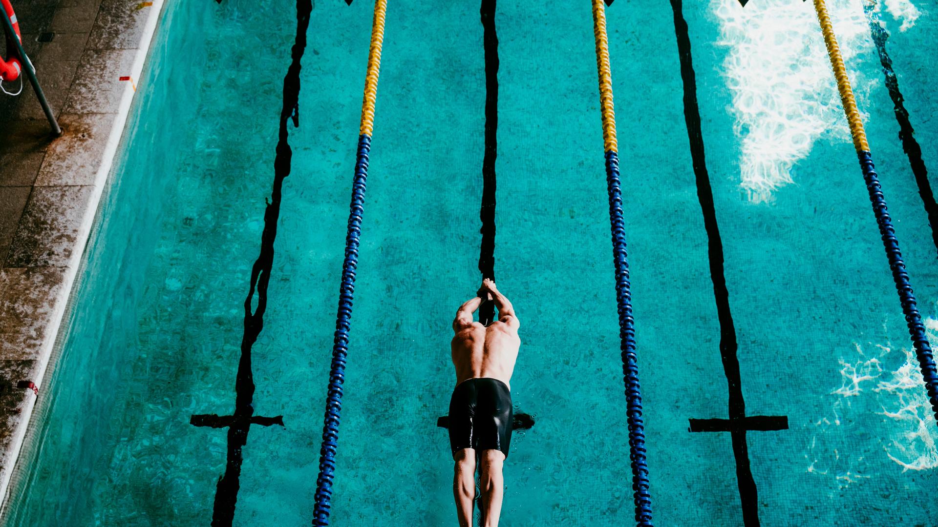Ein Schwimmer springt ins Schwimmbecken Ein Schwimmer springt ins Schwimmbecken