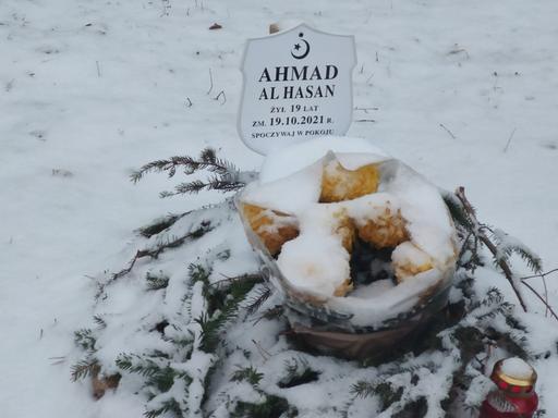 Ein von Schnee bedecktes Grab mit Namenstafel, die an einen an der Grenze zwischen Polen und Belarus gestorbenen Geflüchteten erinnert.