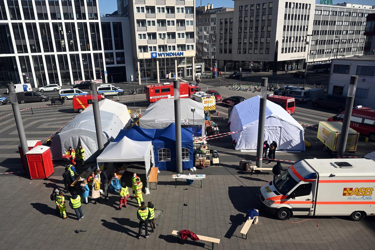 Helferinnen und Helfer, Zelte und mehrere Einsatzfahrzeuge sind hinter dem Kölner Hauptbahnhof aufgereiht, um ankommende Flüchtlinge aus der Ukraine in Empfang nehmen zu können.