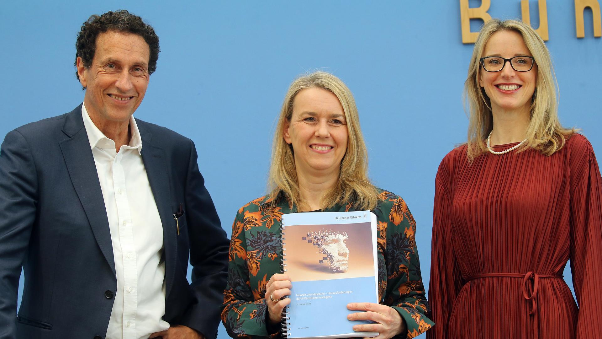 Das Foto zeigt 3 Forscher aus dem Ethik-Rat. Eine Forscherin hält ein Buch in die Höhe. Das Foto zeigt 3 Forscher aus dem Ethik-Rat. Eine Forscherin hält ein Buch in die Höhe.