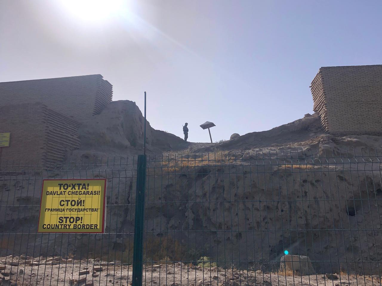 Der Grenzzaun in der Stadt Termiz. Dahinter liegt Afghanistan. Ein Soldat patroulliert im Hintergrund auf einem hohen Erdwall. Der Grenzzaun in der Stadt Termiz. Dahinter liegt Afghanistan. Ein Soldat patroulliert im Hintergrund auf einem hohen Erdwall.